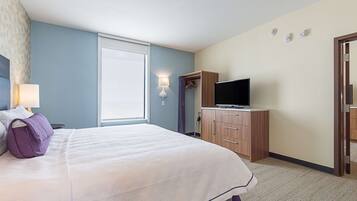 Ein Hotelzimmer mit Bett, Fernseher auf einem Holzkasten, einem Fenster mit Blick und einer Wandleuchte.