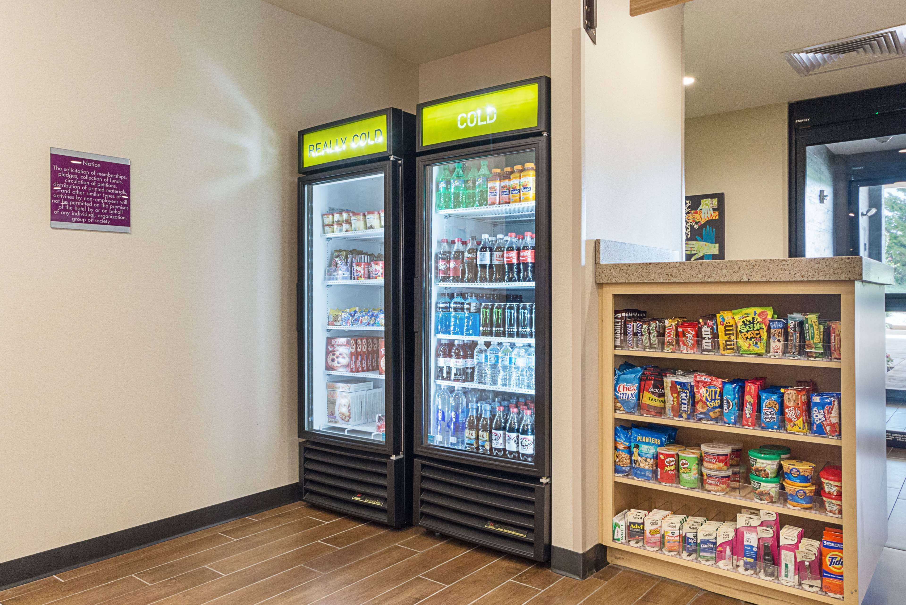 Two refrigerated beverage dispensers labeled "REALLY COLD" and "COLD" with various drinks inside. Adjacent to them is a shelf stocked with snacks and beverages.