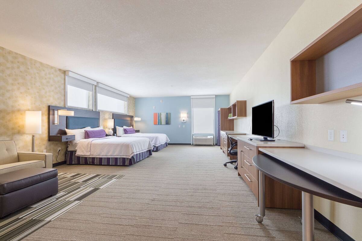 Une chambre d’hôtel avec deux lits, un bureau, une télévision et un canapé.