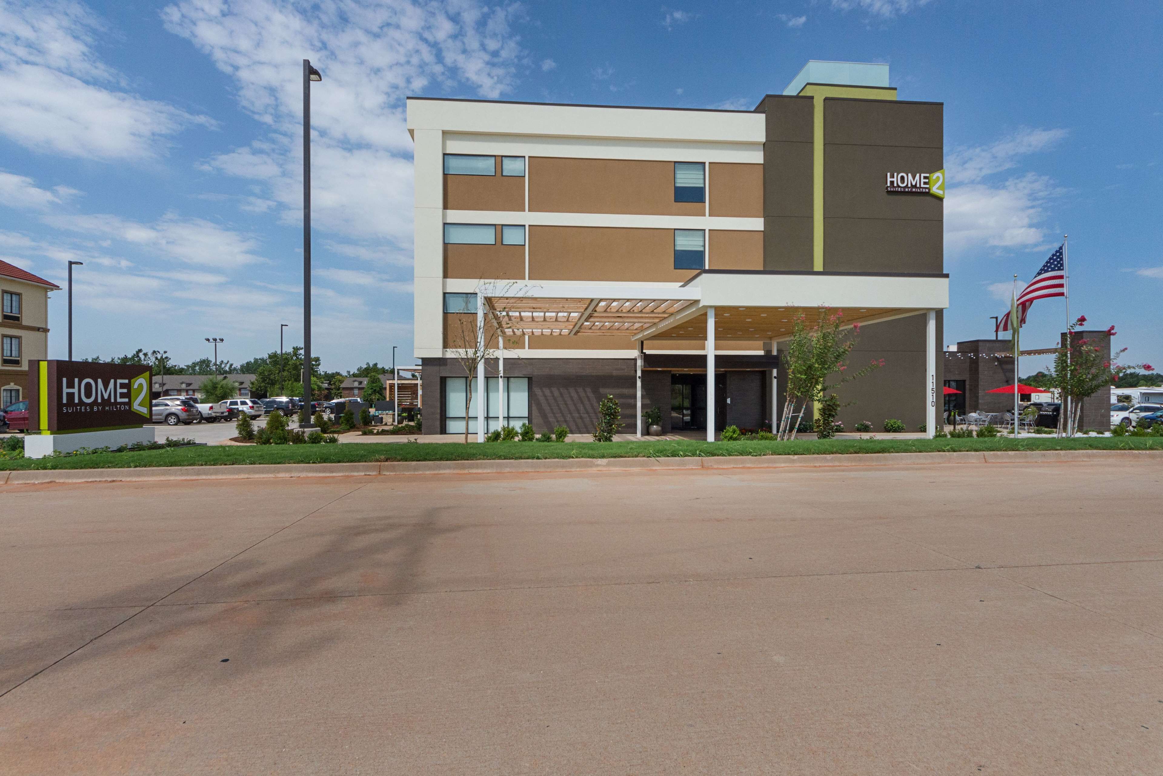 A modern hotel with a two-story structure, a covered entrance, and an American flag.