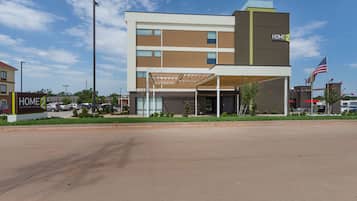 A modern hotel with a two-story structure, a covered entrance, and an American flag.