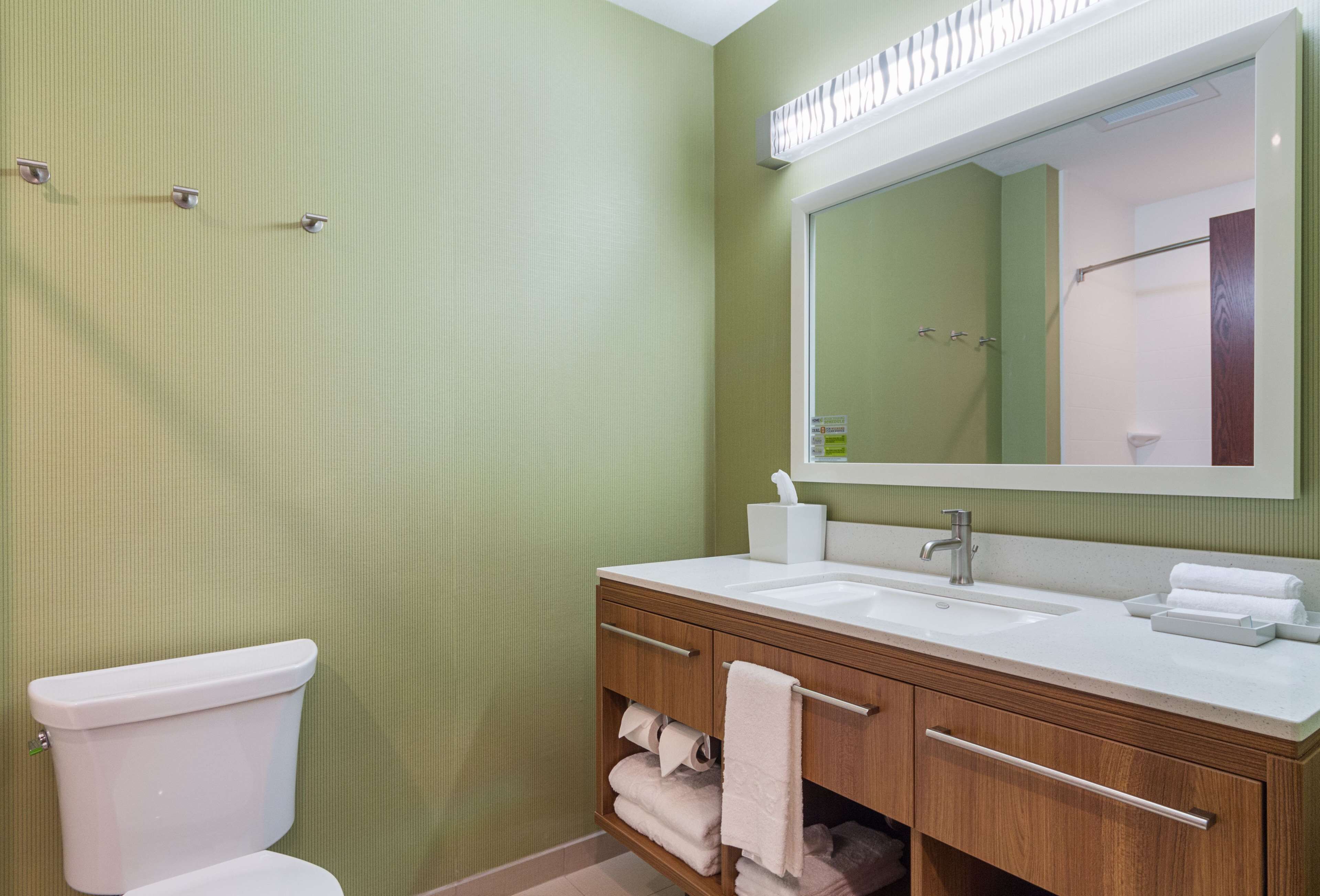 Une salle de bain équipée de toilettes, d’un lavabo, d’un miroir et d’un porte-serviettes.