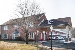 A two-story motel with a brick facade, a covered parking area, and a sign indicating it is an office.