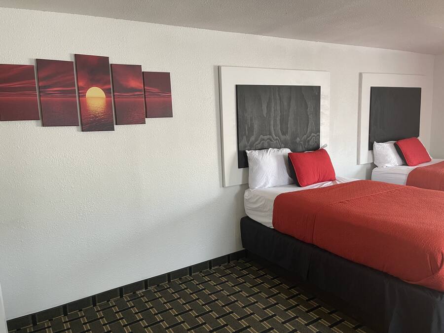 Habitación de hotel con cama, cabecera, una obra de arte colgada en la pared y alfombra estampada.