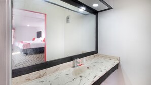 Un baño con un lavamanos blanco, un espejo grande y un marco de puerta rojo.