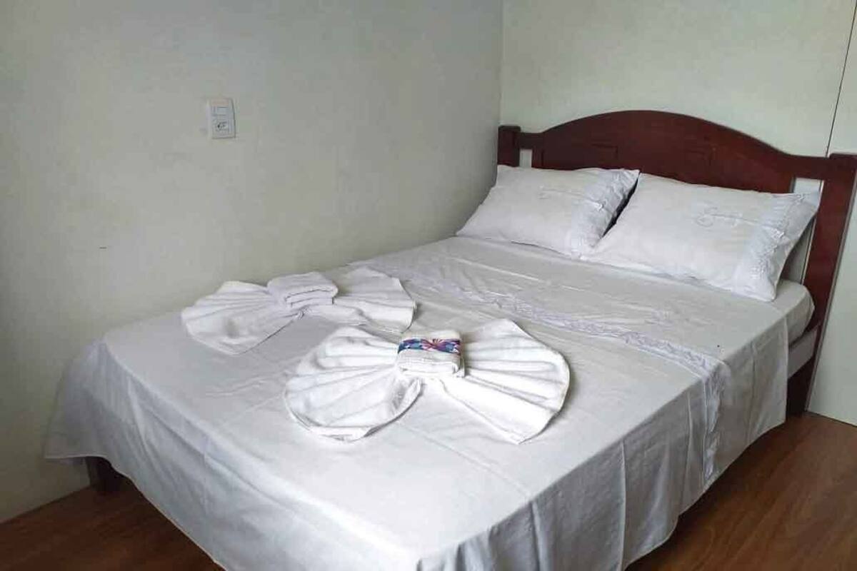 Un lit bien fait, avec des draps blancs et une serviette soigneusement posée sur le lit.