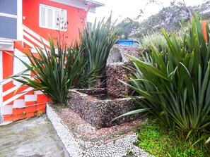 Un jardin agrémenté d’une fontaine en pierre, entouré de grandes plantes vertes.