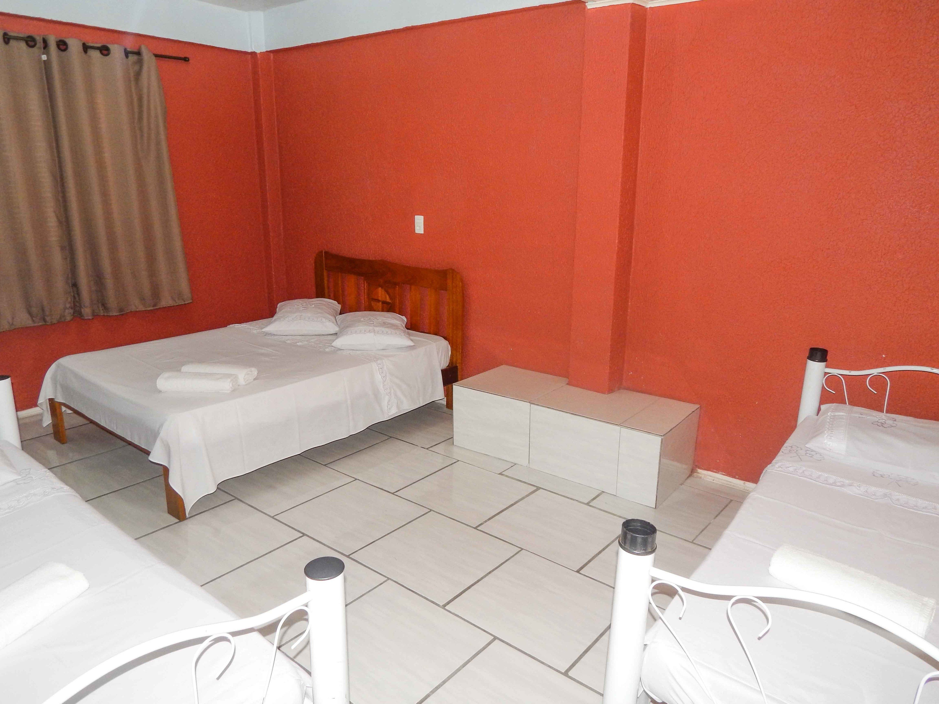 Una habitación de hotel con una cama individual, un banco y una pequeña mesa.