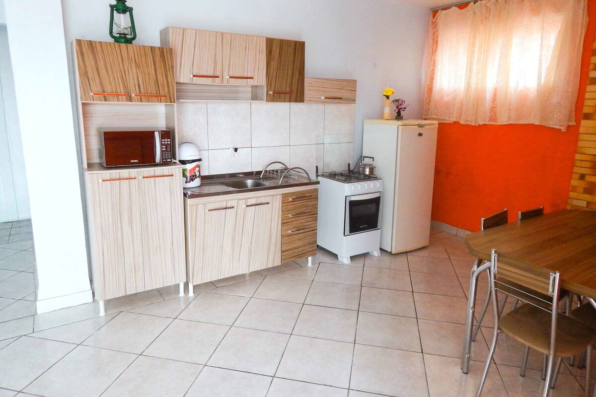 Une cuisine compacte dotée de meubles en bois, d’un four à micro-ondes, d’un évier, d’une cuisinière et d’un réfrigérateur.