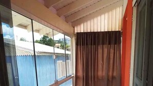 Un balcon avec des carreaux de sol à motifs, une porte vitrée et une vue sur un immeuble bleu.