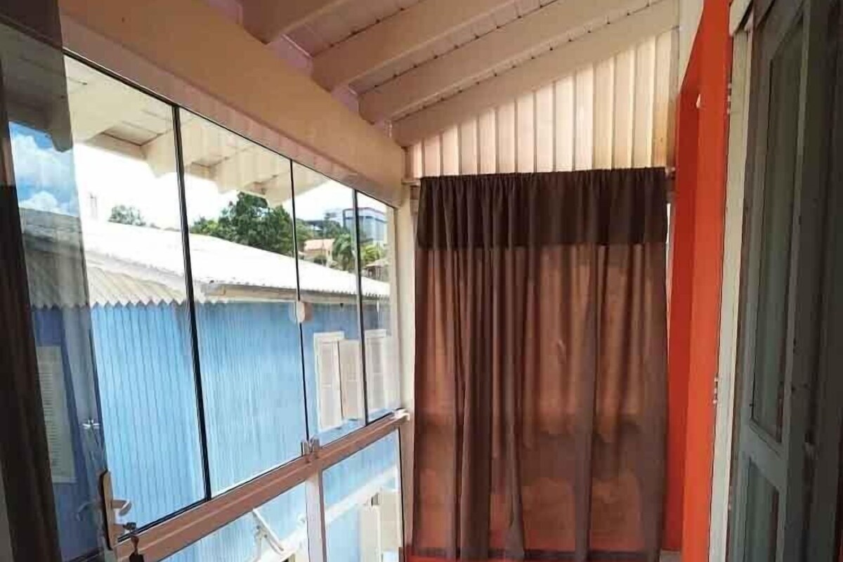 Un balcon avec des carreaux de sol à motifs, une porte vitrée et une vue sur un immeuble bleu.