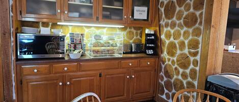 Una cocina con armarios de madera, microondas, tostadora y una exposición de pan.