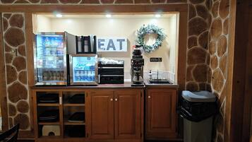 Una kitchenette con refrigerador, cafetera y un letrero que dice 'EAT'.