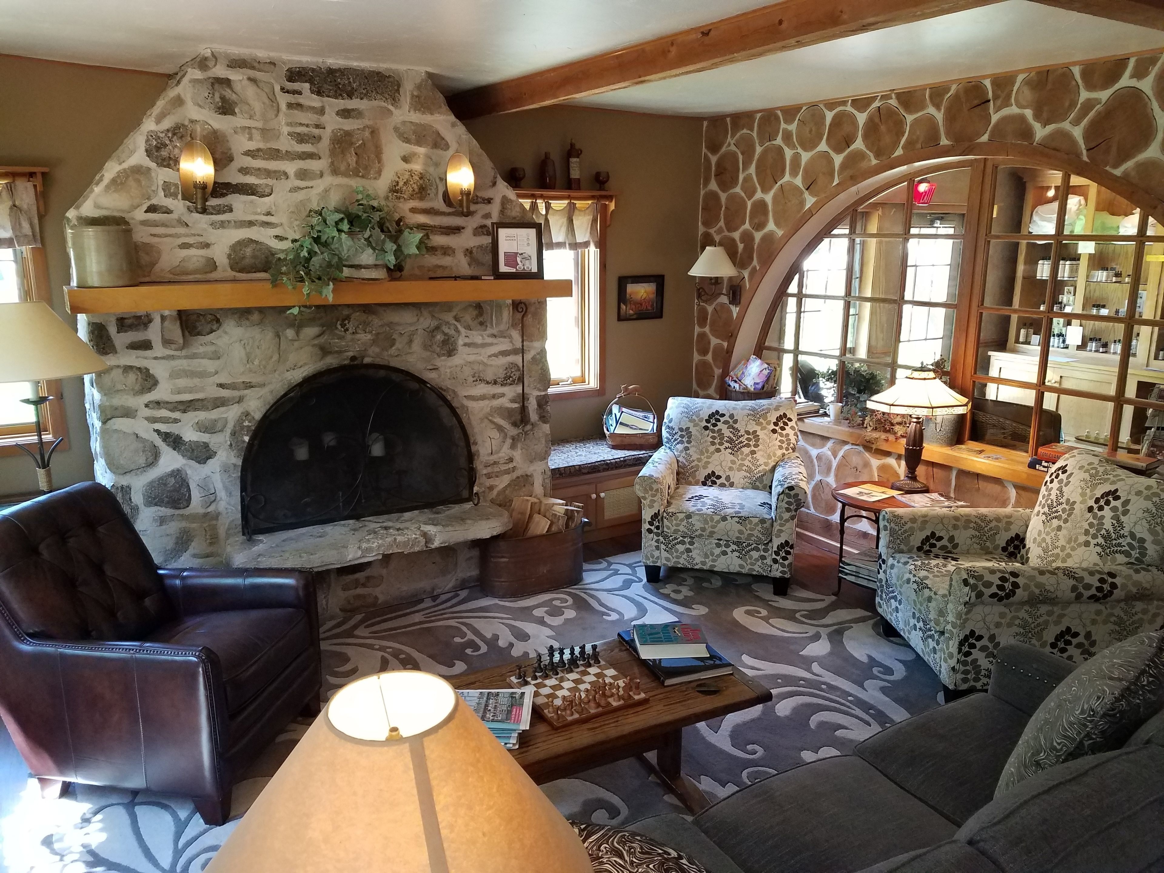 A cozy living room with a stone fireplace, comfortable seating, and a chessboard.