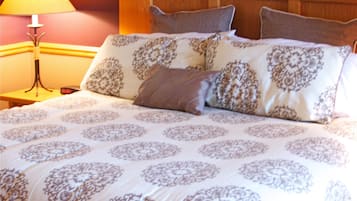 A neatly made bed with patterned bedding, a wooden headboard, and a bedside lamp.