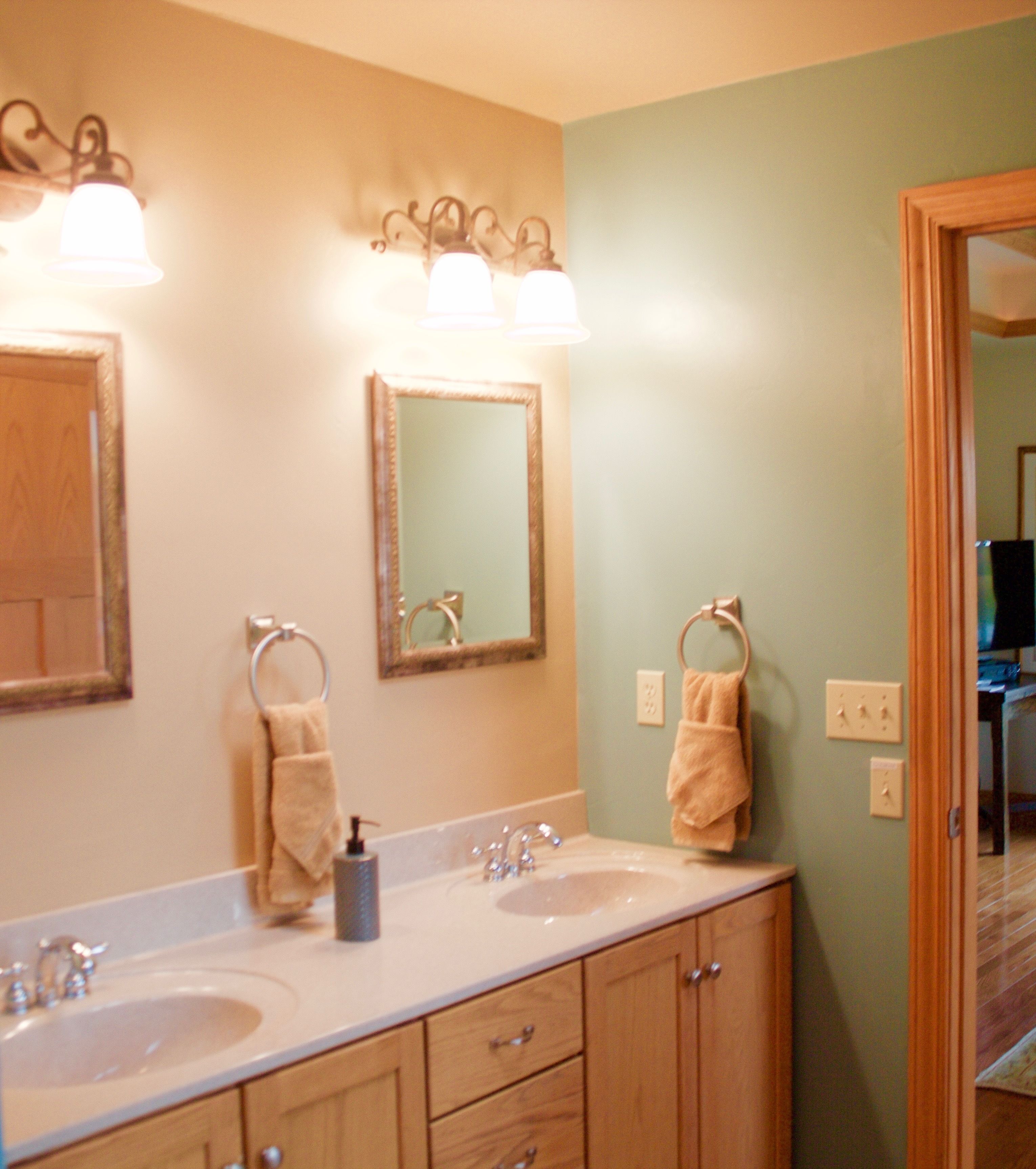 A bathroom with two sinks, a mirror, and a towel rack.