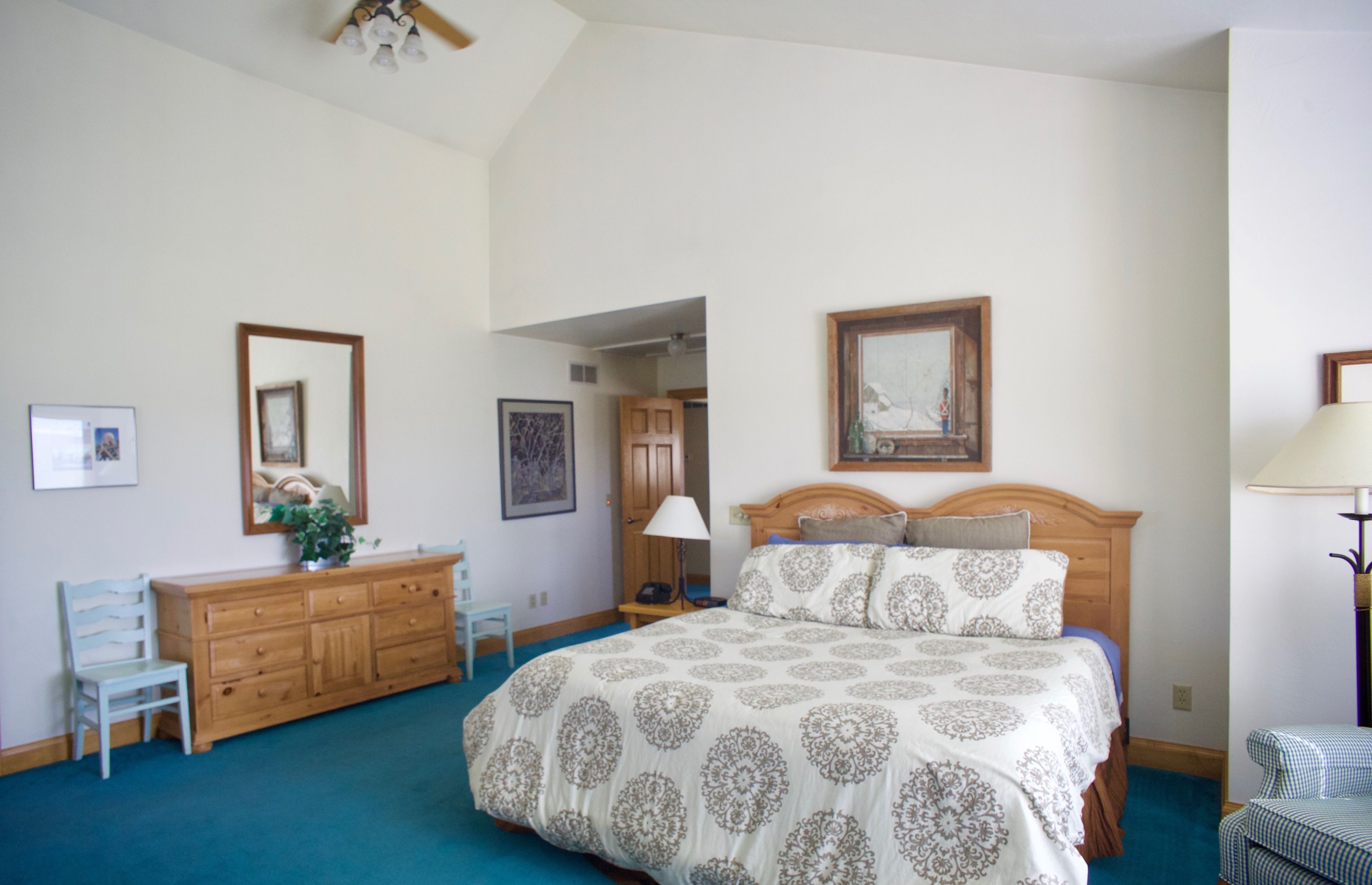 A bedroom with a large bed, wooden dresser, and a mirror on the wall.