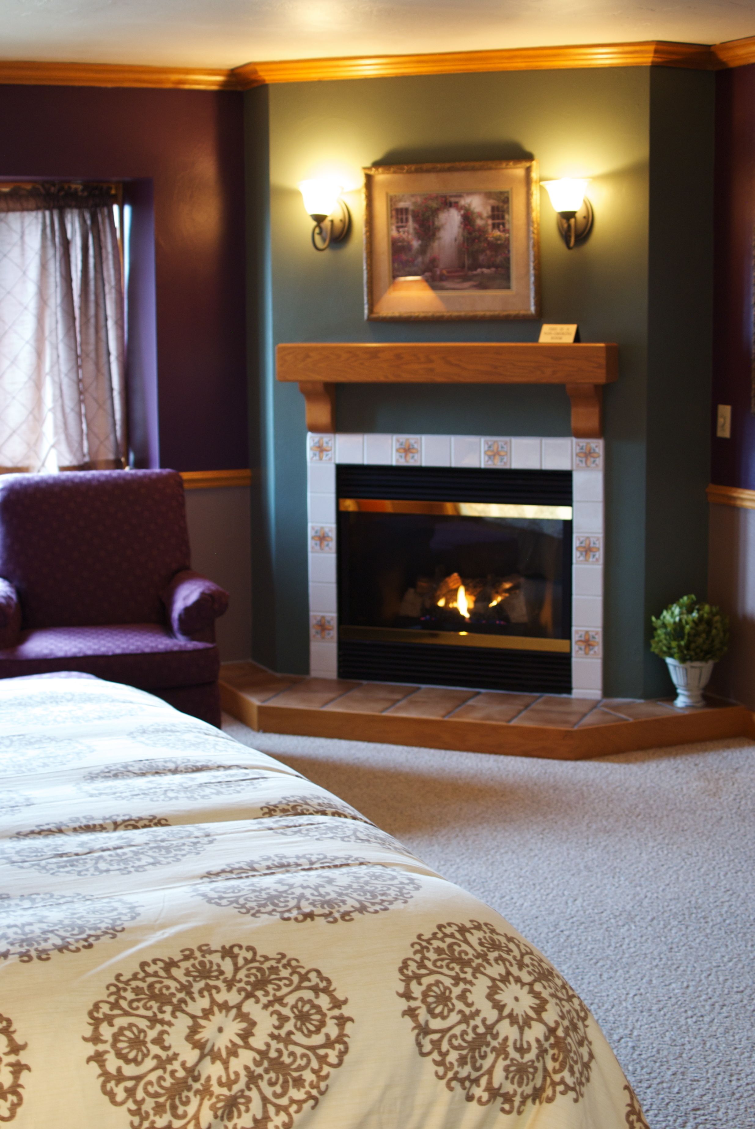 Una habitación de hotel con chimenea, una silla y una cama con colcha estampada.