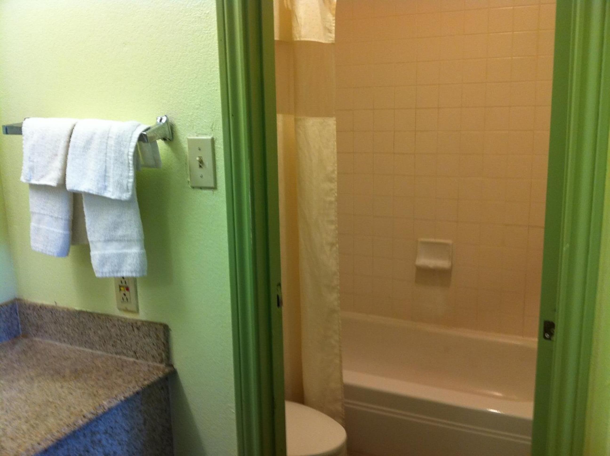 A bathroom with a toilet, a shower, and a towel rack with towels.