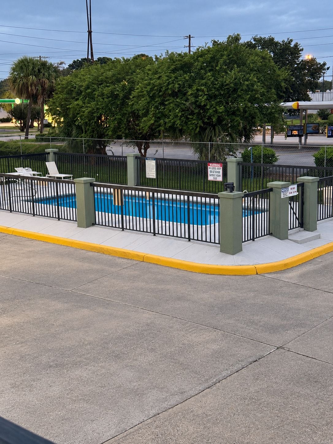 Zona de piscina cercada, con vista despejada a la calle y la vegetación circundante.