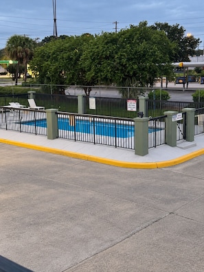 A fenced pool area with a clear view of the surrounding street and greenery. - America's Best Inn (Savannah)