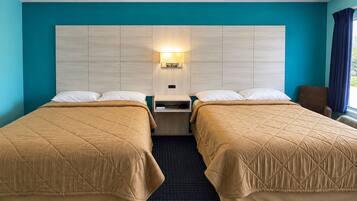 Camera d'albergo con due letti, un comodino, una lampada a parete e una finestra con tende.
