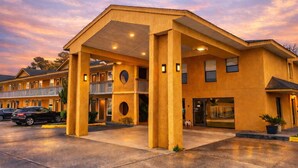 Ein Motel mit zentralem Eingang, zahlreichen Fenstern und einem Parkplatz.