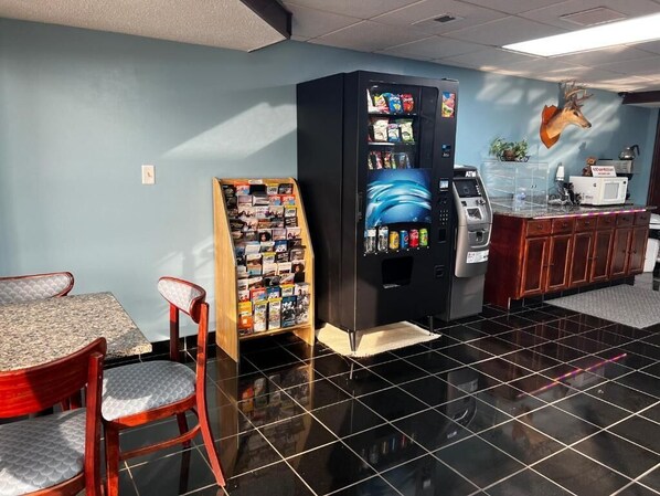 A restaurant with a black tiled floor, a vending machine, a wooden display rack, and a wall-mounted deer head decoration. - America's Best Inn (Savannah)