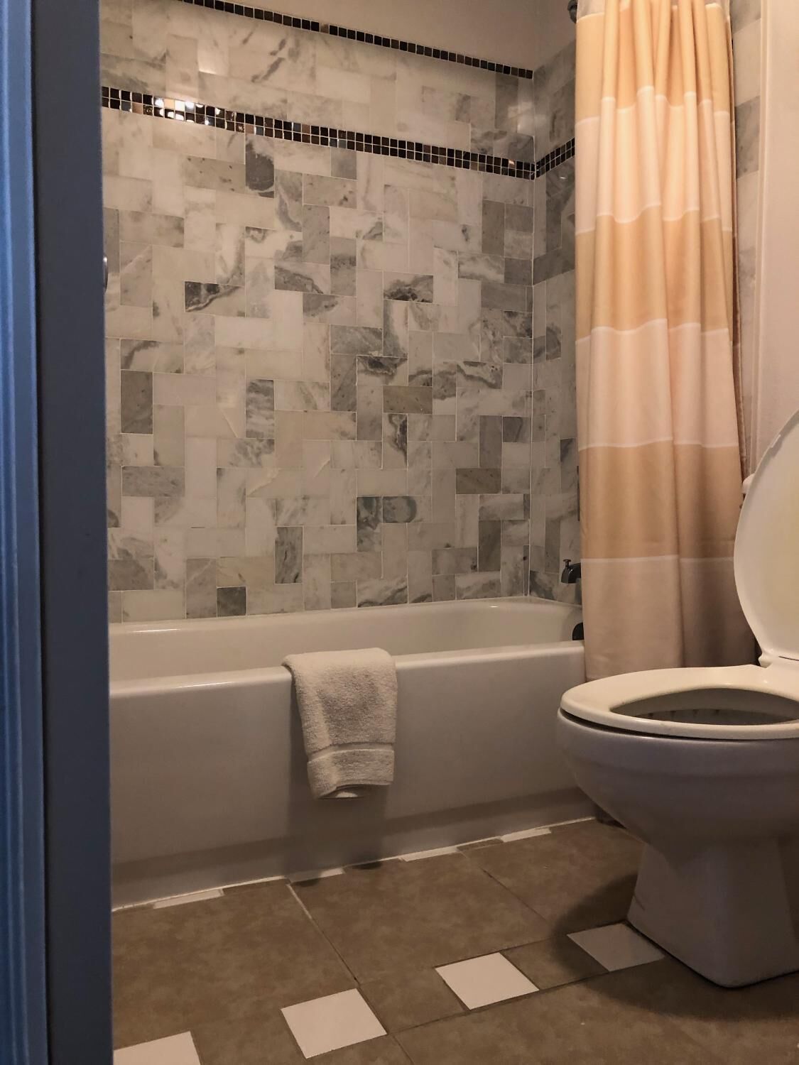Een badkamer met een bad, toilet en een douchegedeelte met mozaïektegels.