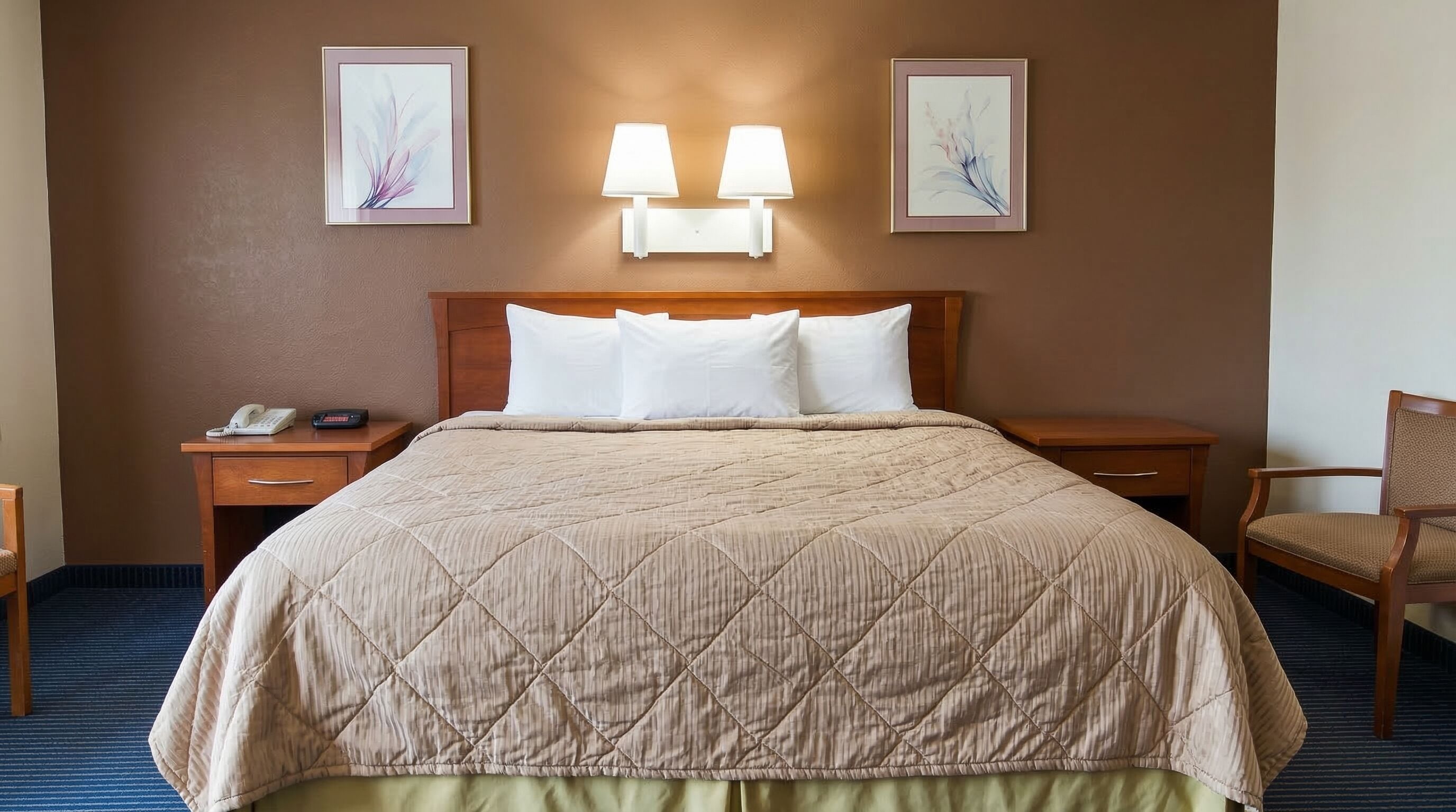 Ein Hotelzimmer mit einem Bett, zwei Nachttischen, einem Sessel und Wandleuchten.