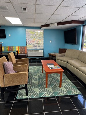 A living room with a sofa, chairs, a coffee table, a television, and a patterned rug. - America's Best Inn (Savannah)