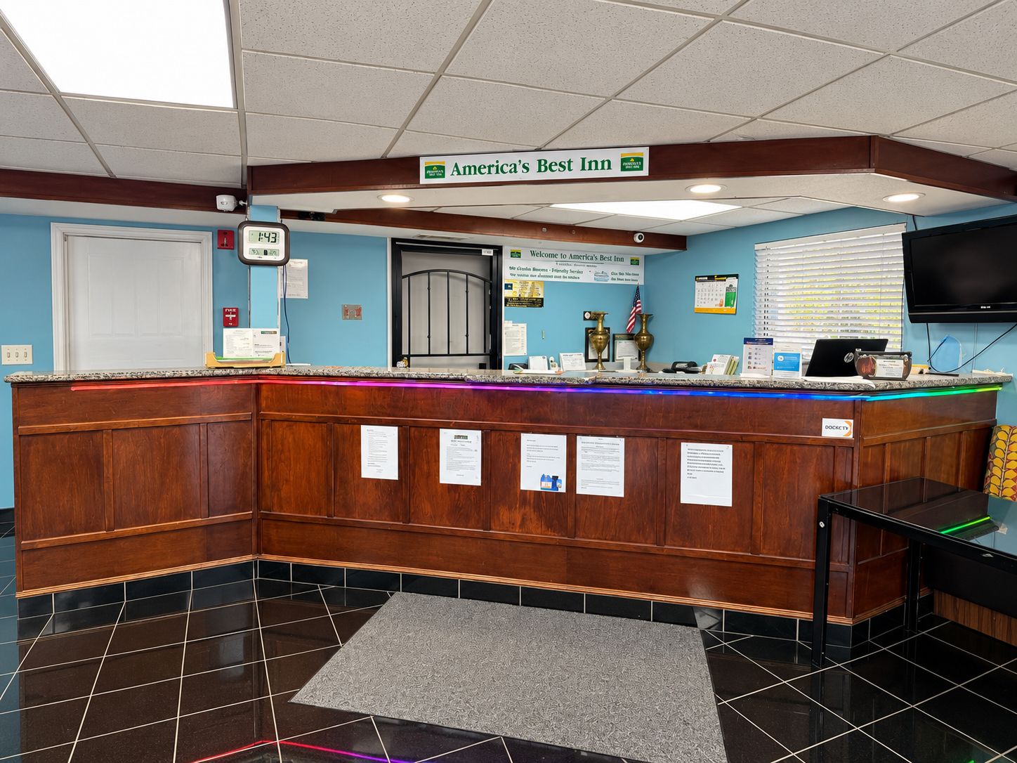 A reception desk with a sign reading 'America's Best Inn' and a digital clock displaying 1:43.