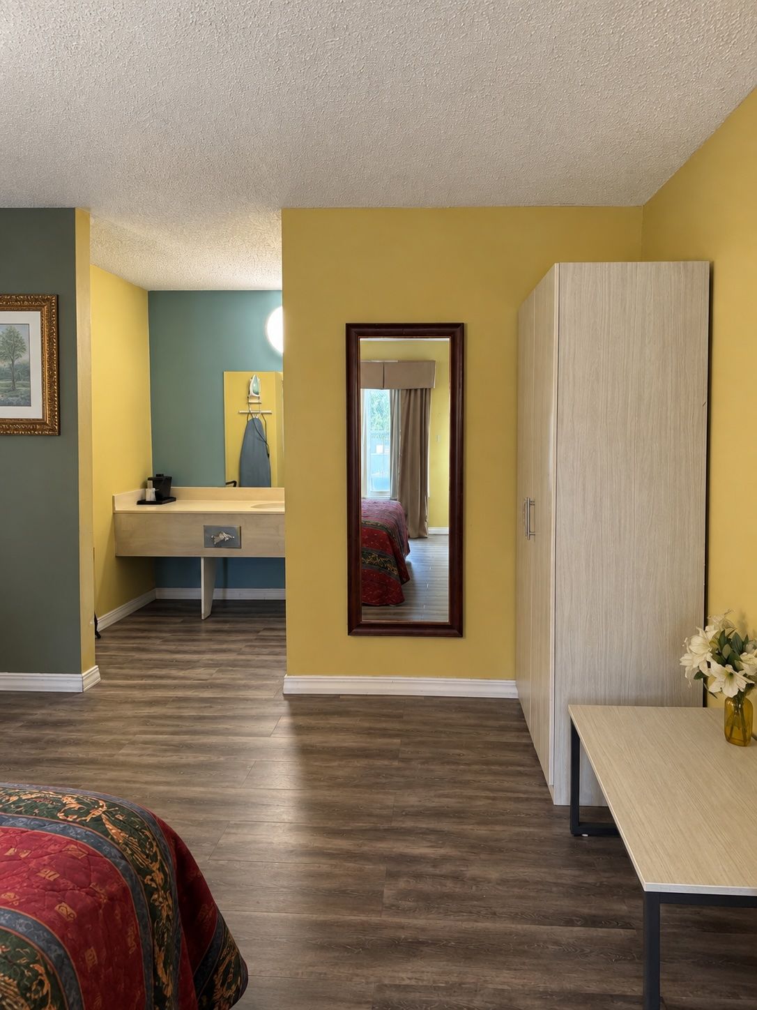 A bedroom with a bed, a desk, a wardrobe, and a mirror.