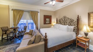 Habitación de hotel con una cama grande, un sofá, una silla, una mesa y vistas a la ciudad.