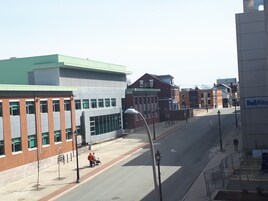 A street view with buildings, a clear sky, and a pedestrian crossing.