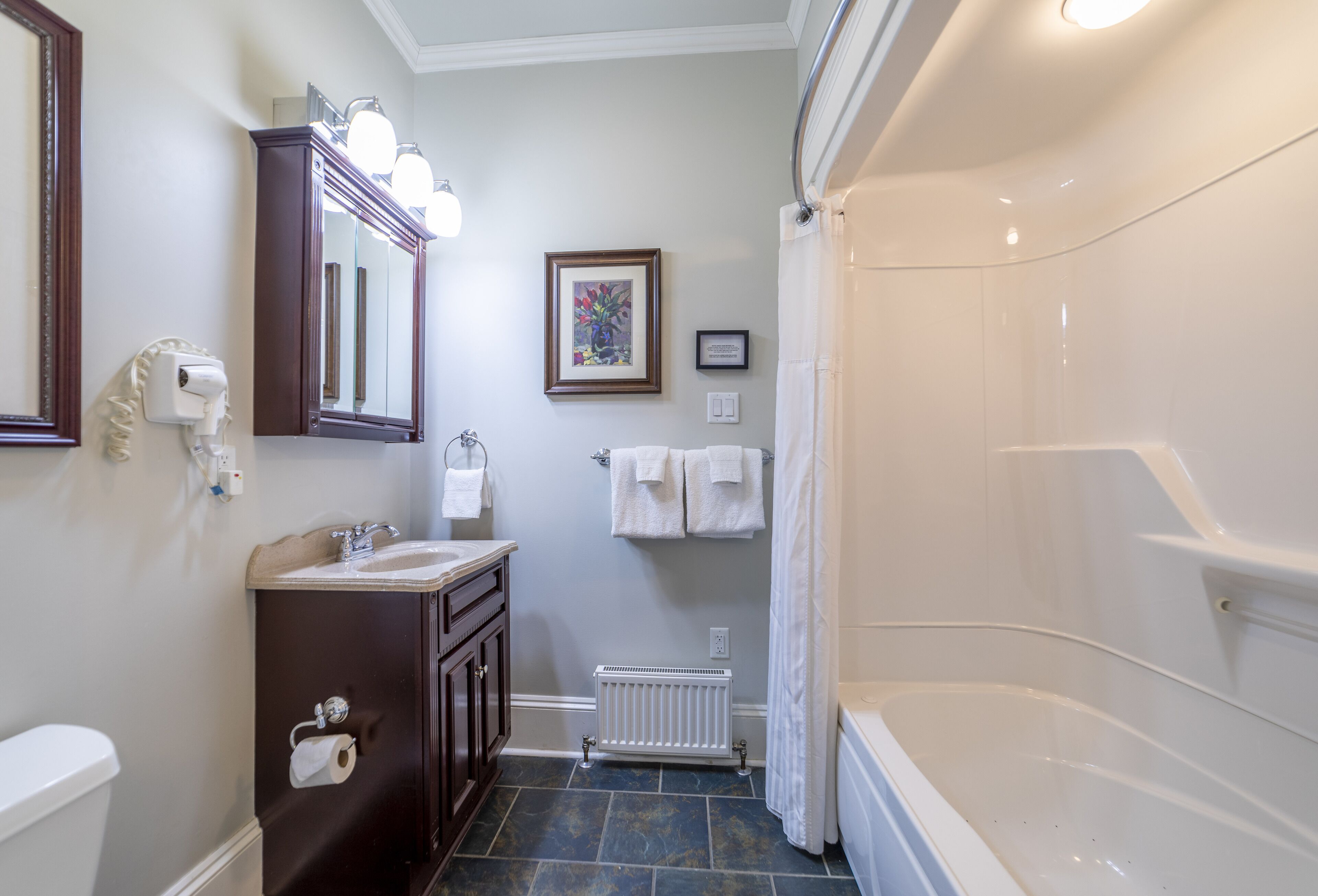 Une salle de bain équipée d’une baignoire, d’un lavabo, de toilettes, d’un miroir et d’un radiateur.