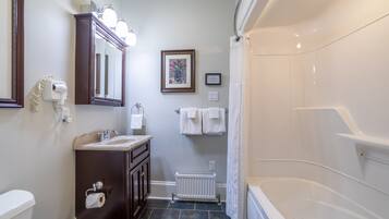 Une salle de bain équipée d’une baignoire, d’un lavabo, de toilettes, d’un miroir et d’un radiateur.