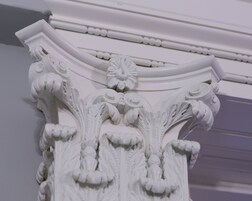 A detailed white architectural column with ornate carvings and a decorative capital.