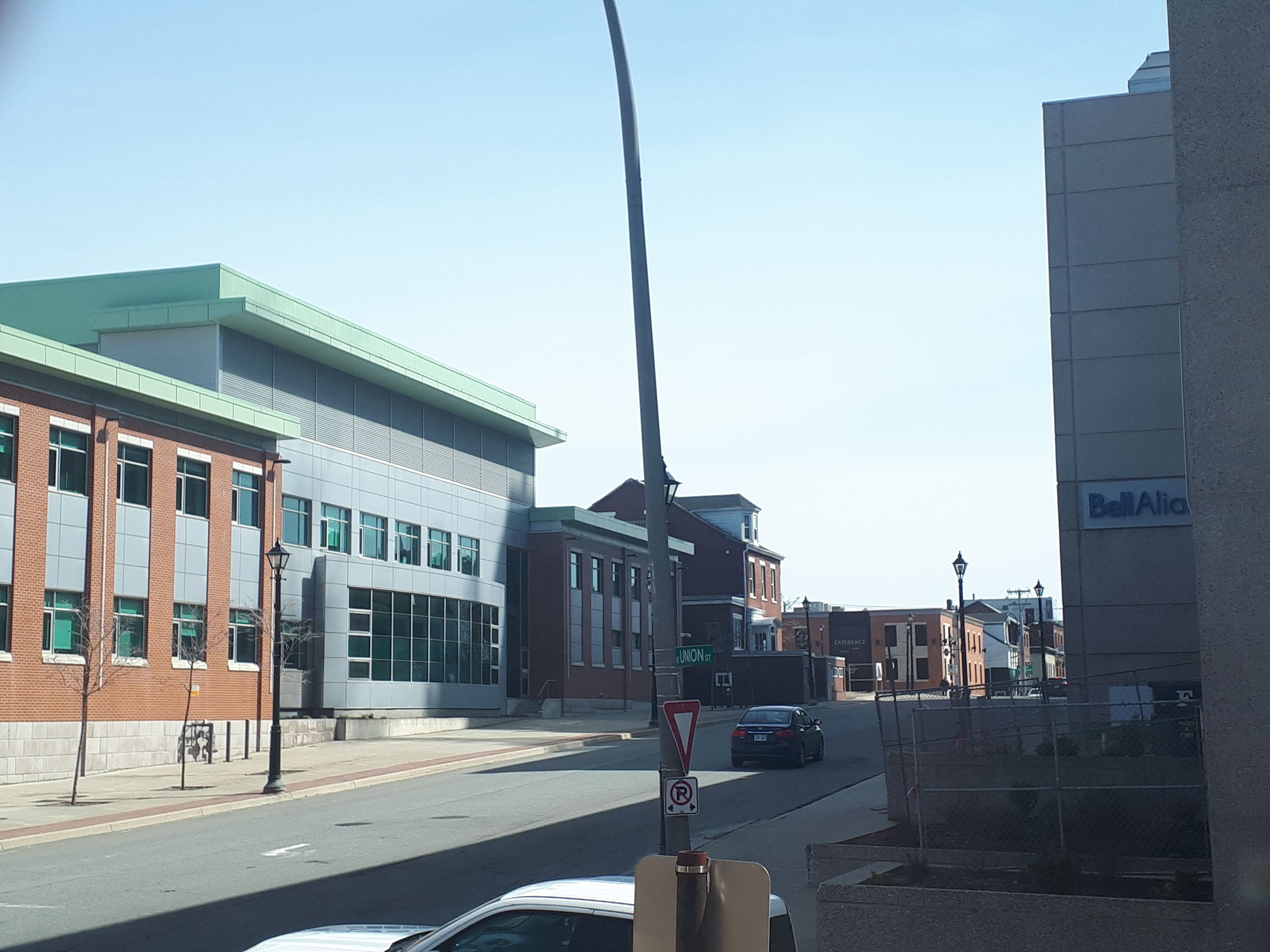 A street view with buildings, a car, and a no parking sign.