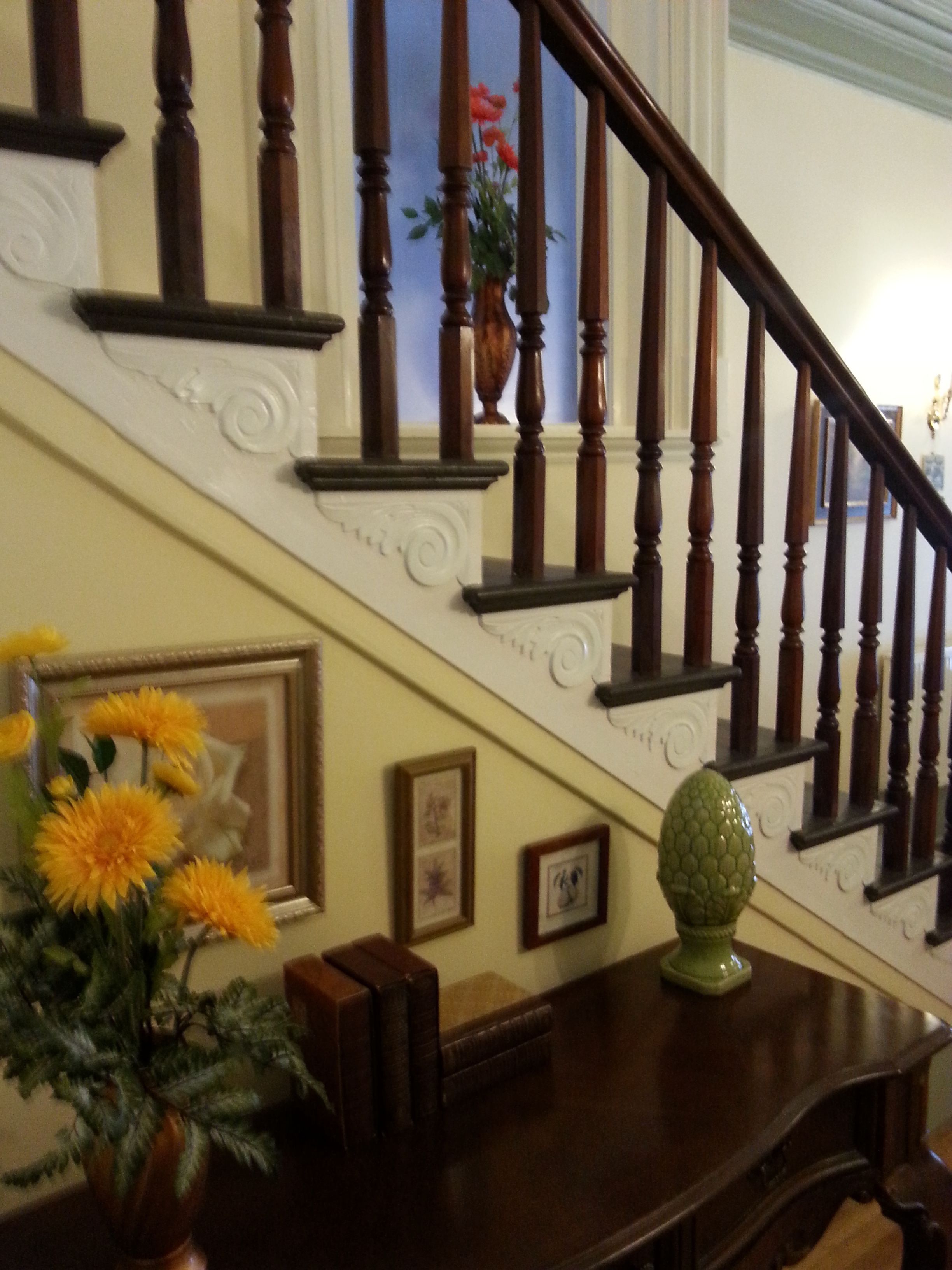 A wooden staircase with a vase of flowers on the landing.