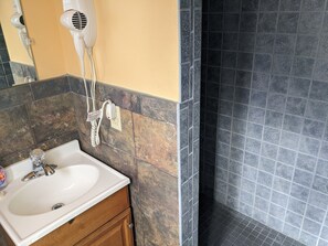 Un baño con lavamanos, tocador y un secador de pelo enchufado.