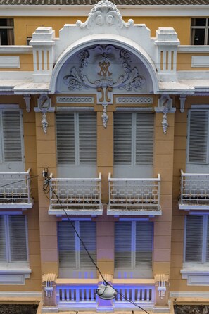 A building with ornate white balconies and shutters, a decorative archway, and a stone base. - Hotel Joamar (Sao Paulo)