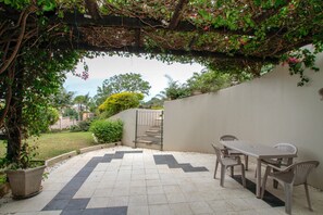 A patio with a tiled floor, a table and chairs, and a pergola with climbing plants. - Chartwell Guest House (Umhlanga)
