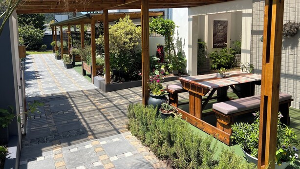 A covered patio area with wooden benches and potted plants. - Pelican Lodge (Sedgefield)
