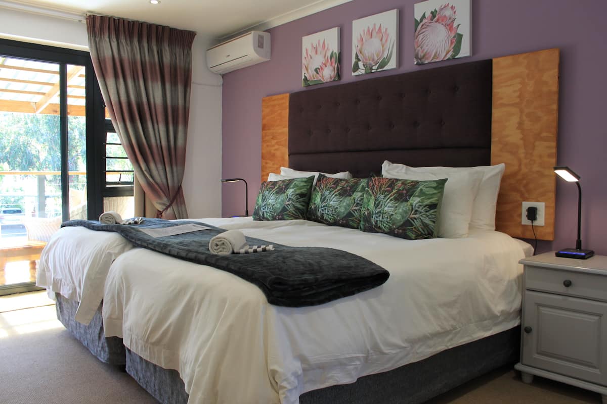 A bedroom with a large bed, a nightstand, a lamp, and a window with curtains.