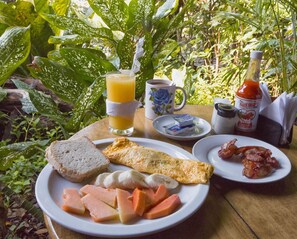 A breakfast setting with a plate of toast, ham, eggs, and a glass of orange juice. - Hotel Hacienda Tijax (Livingston)