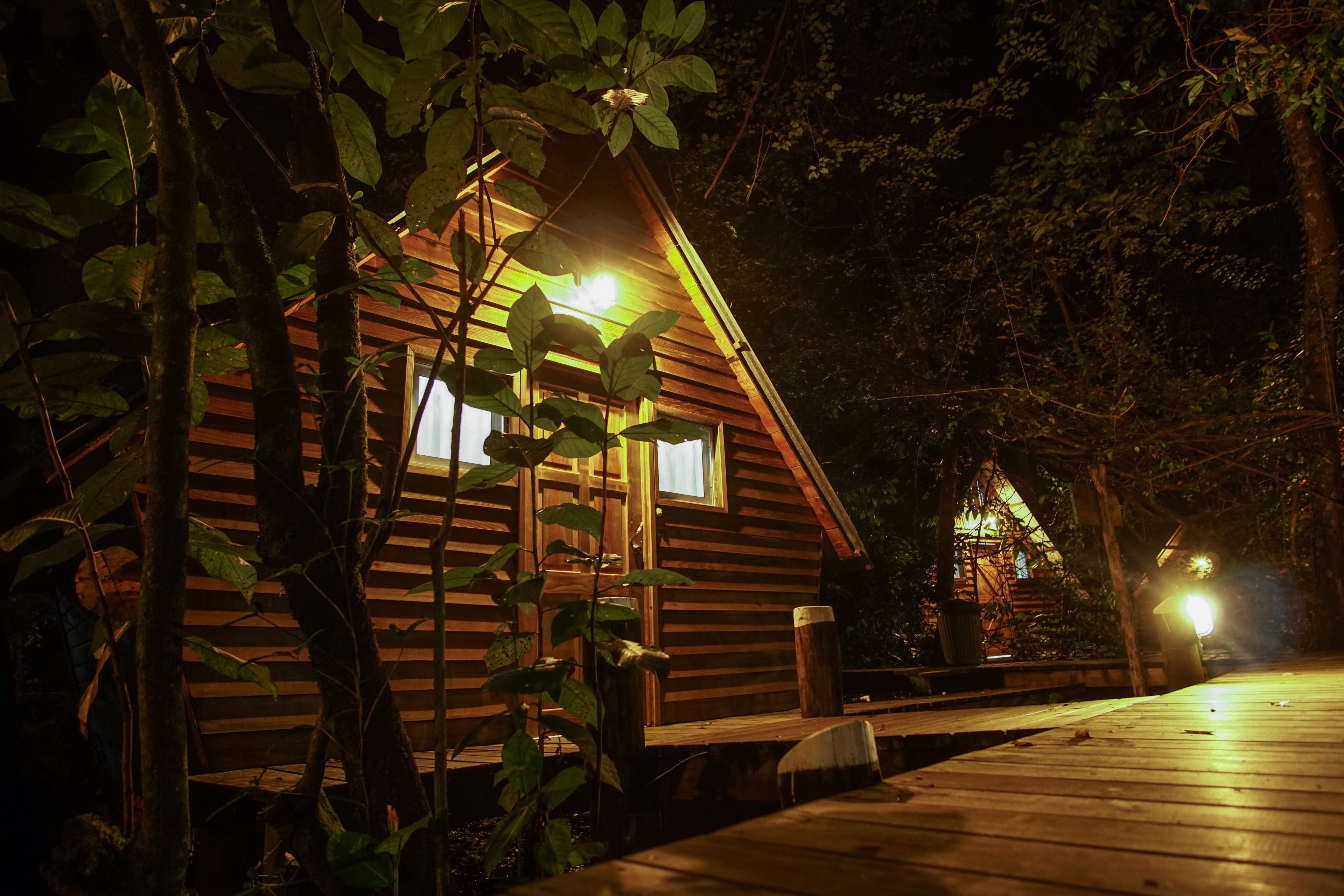 A wooden cabin with a porch, surrounded by trees.