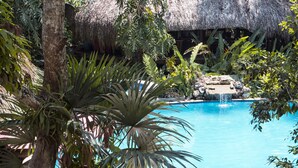 A pool surrounded by tropical vegetation and a wooden deck. - Hotel Hacienda Tijax (Livingston)