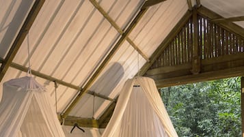 A tented accommodation with two beds, each with a canopy.