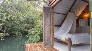 A wooden deck with a bed and a mosquito net. - Hotel Hacienda Tijax (Livingston)